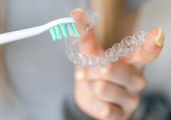 Patient using toothbrush to clean aligner