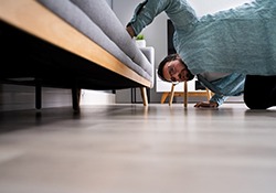 Man looking for something under couch