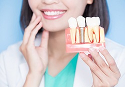 dentist holding a model that shows how dental implants work in Downers Grove