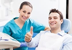 Smiling man in dental chair giving thumbs up