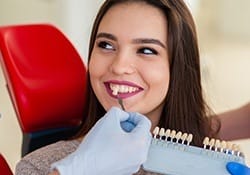 Woman's smile compared with tooth color chart