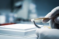A dental lab technician processing a dental crown