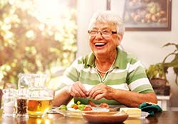 Smiling woman at dinner table with dentures in Downers Grove