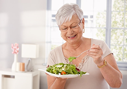 a woman with dentures eating a healthy meal
