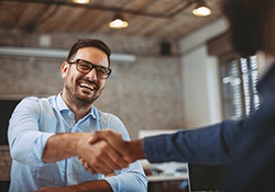 a man smiling with dentures and shaking someone’s hand