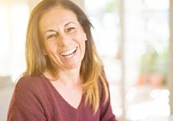 Woman in burgundy sweater with brown hair smiling