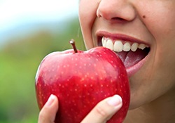 close up of woman who is eating a red apple