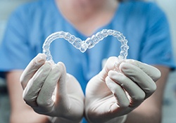 dentist holding Invisalign aligners in a heart shape