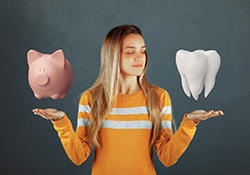 Woman holding illustration of piggy bank and model tooth