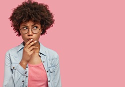 Wondering woman on pink background with her hand on her mouth