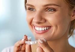 Smiling, healthy woman holding Invisalign