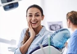 A young woman smiling in the dentist’s chair because of her new metal-free restoration