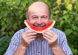 Man preventing dental emergencies in Downers Grove by eating a watermelon
