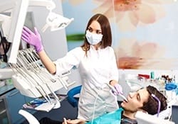 Dentist and man in dental chair looking at tooth images on computer