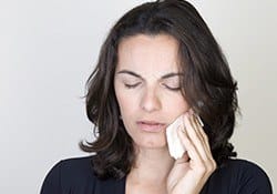 Woman holding cold compress to cheek