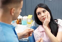 A woman with mouth pain listening to a dentist.