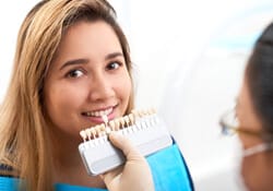 dentist holding a row of veneers in Downers Grove to a patient’s smile
