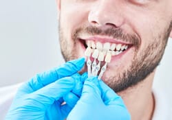 dentist holding veneers over a patient’s smile