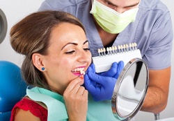 dental patient holding veneers up to her smile