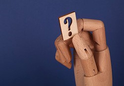 Wooden hand holding a question mark